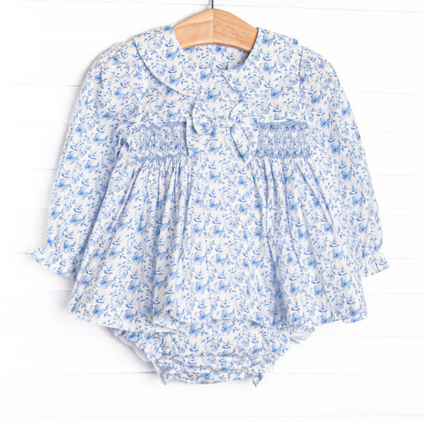 This set features a blue floral fabric, dainty smocking, a floral peter pan collar, and a pre tied bow.