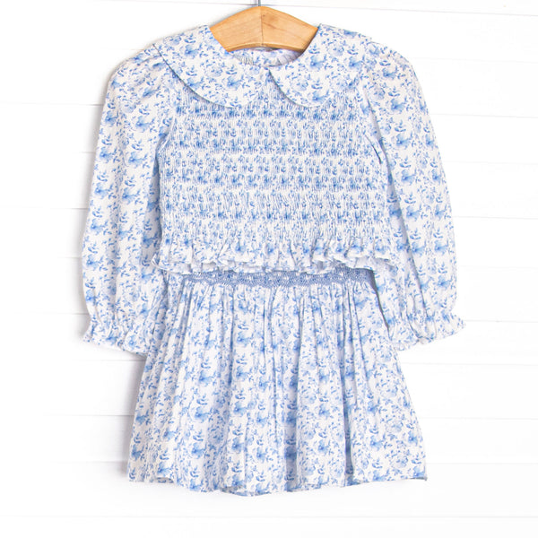 This set features a blue floral fabric, floral smocking, a peter pan collar, and a matching skirt.