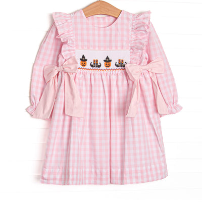 This dress features pink gingham fabric, Halloween smocking, and pink side ties.