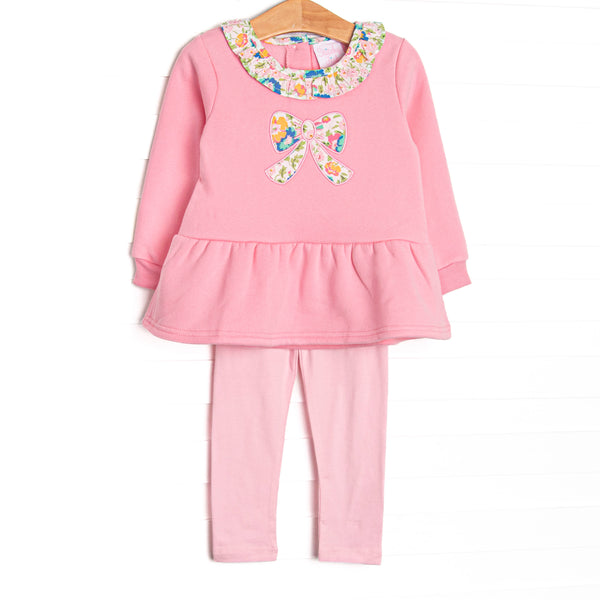 This sweatshirt set features pink knit fabric, floral ruffle trim, and a floral bow applique. Coordinating pink leggings to match.