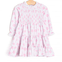  This dress features pink floral print, chest smocking, and eyelet lace trim. 
