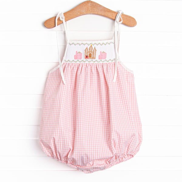  This bubble features a pink gingham print, shoulder ties, and castle smockings. 