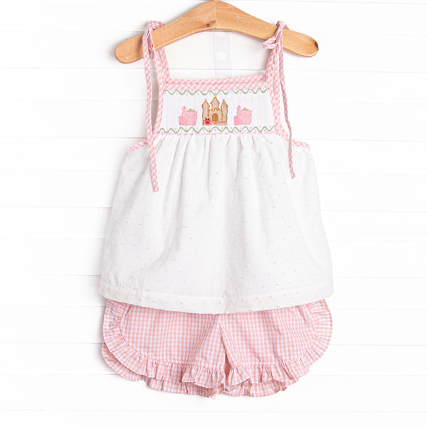This set features a swiss dot top with a castle smocking and shoulder ties. Coordinating pink gingham ruffle shorts to match.