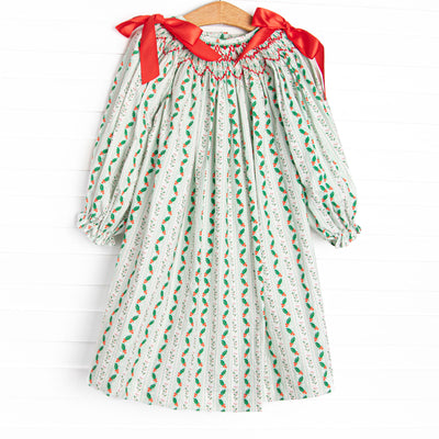 This dress features a holly print, red bows, and a dainty smocking.