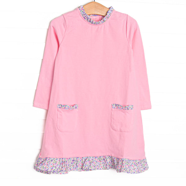  This dress features pink knit fabric, front ruffle pockets, and floral ruffle trim. 
