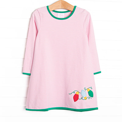 This dress features a pink striped print, green trim, and Christmas light appliques.