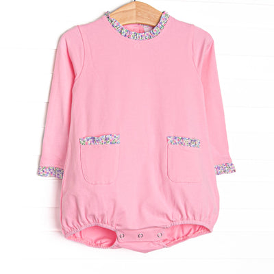  This bubble features pink knit fabric, front ruffle pockets, and floral ruffle trim. 
