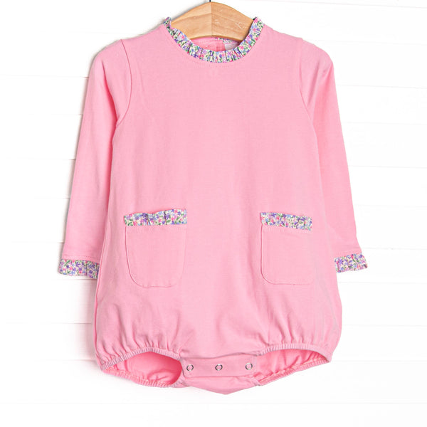  This bubble features pink knit fabric, front ruffle pockets, and floral ruffle trim. 