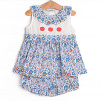 his set features a blue floral print, a ruffle collar, and a trio of apple appliques.