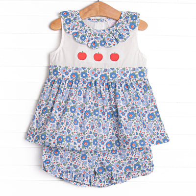 his set features a blue floral print, a ruffle collar, and a trio of apple appliques.