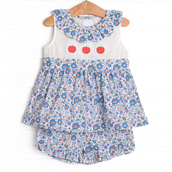 his set features a blue floral print, a ruffle collar, and a trio of apple appliques.