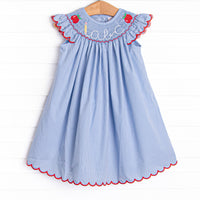 This dress features a blue gingham print, red ric rac trim, and an apple and abc smocking.