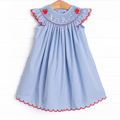 This dress features a blue gingham print, red ric rac trim, and an apple and abc smocking.