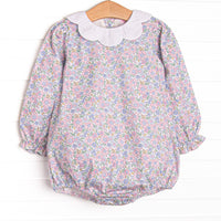  This bubble features a pink floral print, a white scalloped bib collar and ruffle hems. 