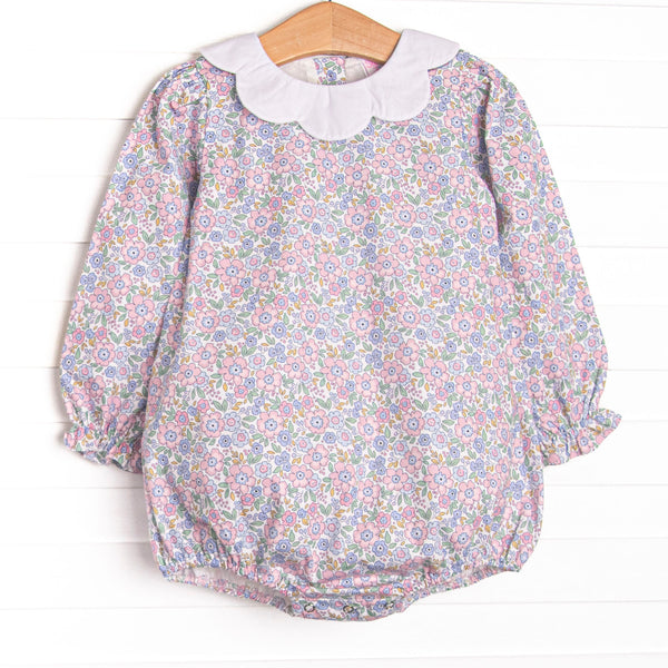  This bubble features a pink floral print, a white scalloped bib collar and ruffle hems. 