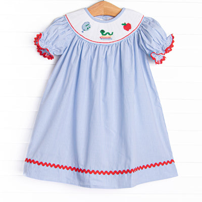 This dress features a blue striped print, red ric rac trim, and a school smocking.