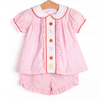 This set features pink material, puff sleeves, and abc and apple embroidery. Pink ruffle shorts to match