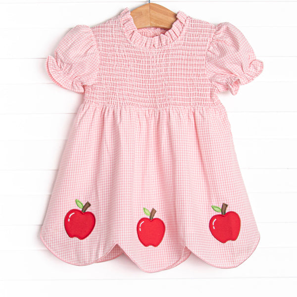 This dress features a pink gingham print, puff sleeves, and apple trio applique.