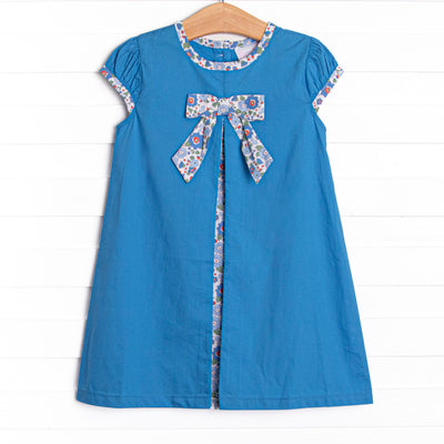  This dress features a blue floral bow, puff sleeves, and blue floral print inside of the pleat. 