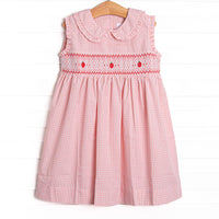  This dress features a pink gingham print, a peter pan collar, and an apple smocking. 