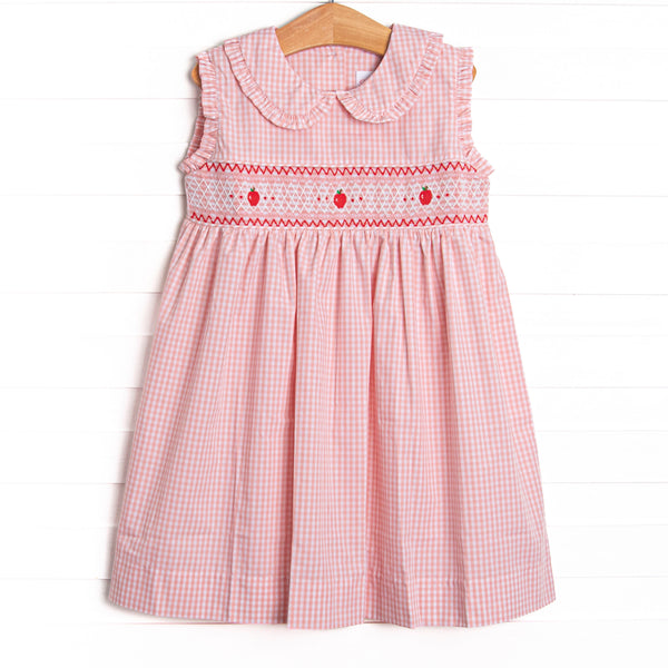  This dress features a pink gingham print, a peter pan collar, and an apple smocking. 