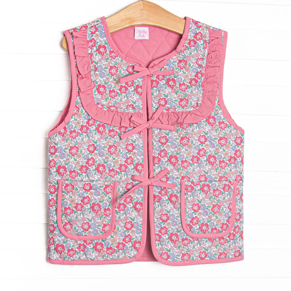  This reversable vest features pink fabric on one side, pink floral fabric on the other, a tie front, and front pockets. 