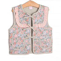 This reversable vest features sage fabric on one side, pink floral fabric on the other, a tie front, and front pockets.