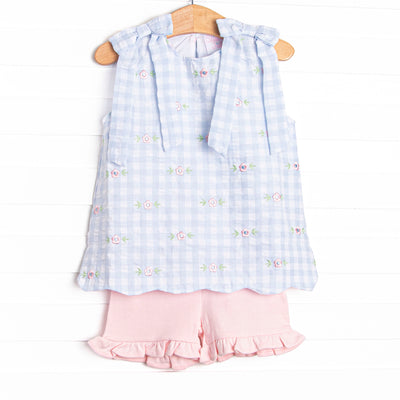 This dress featues a blue check print, shoulder ties, and a floral embrodiery. Coordinating pink ruffle shorts to match!