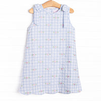 This dress featues a blue check print, scalloped trim, and a floral embrodieries.
