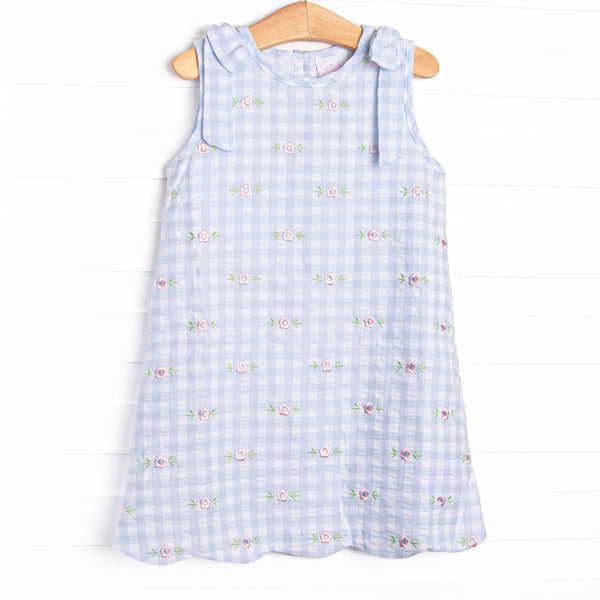 This dress featues a blue check print, scalloped trim, and a floral embrodieries.