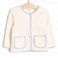 This coat features a cream fleece fabric, blue gingham trim, and clear front buttons.