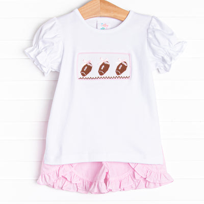  This set features short puff sleeve top with a trio of football smocking and pink mini gingham ruffle shorts to match. 