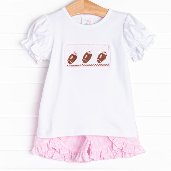  This set features short puff sleeve top with a trio of football smocking and pink mini gingham ruffle shorts to match. 