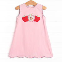 This dress features a pink knit material, scalloped trim, and a trio of apple appliques.