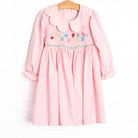  This dress features a pink gingham print, a scalloped collar, and a smocking of Christmas lights. 