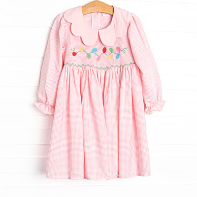  This dress features a pink gingham print, a scalloped collar, and a smocking of Christmas lights. 