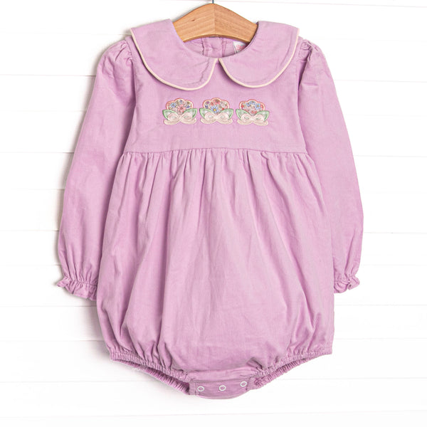 This bubble features purple corduroy fabric, floral appliques, a purple Peter Pan collar, and a sash tie back.