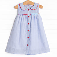 This dress features a blue seersucker print, red trim, and a peter pan collar.