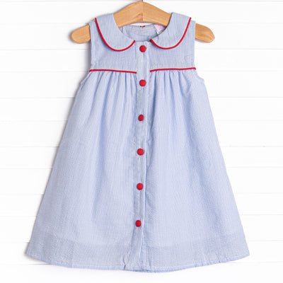 This dress features a blue seersucker print, red trim, and a peter pan collar.
