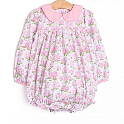 This bubble features a pink hydrangea print, a pink Peter Pan collar, and snaps on the stride.
