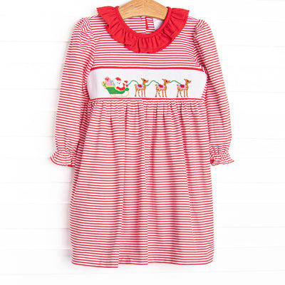This dress features a red striped print, a red ruffle collar, and a smocking of Santa's Sleigh.