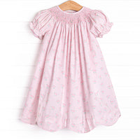 his dress features a rose print, puff sleeves, and a dainty smocking.