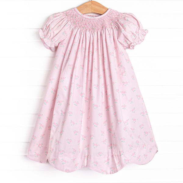 his dress features a rose print, puff sleeves, and a dainty smocking.