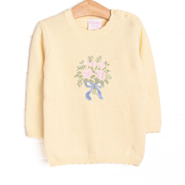 This sweater features yellow fabric, a floral bouquet icon, and yellow buttons on the shoulder.