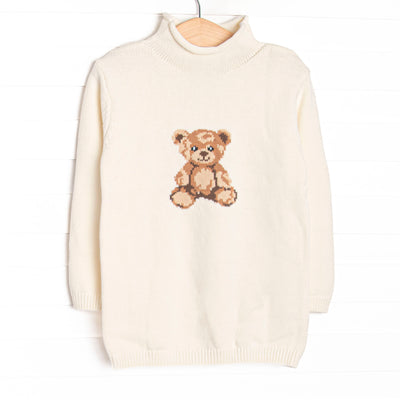 This sweater features white fabric, a rolled neck, and a teddy bear icon.