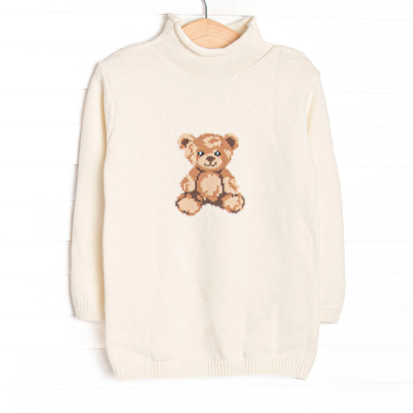 This sweater features white fabric, a rolled neck, and a teddy bear icon.