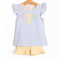 This set features a flutter sleeves top in a blue striped print, a seahorse applique, and yellow ruffle shorts to match.