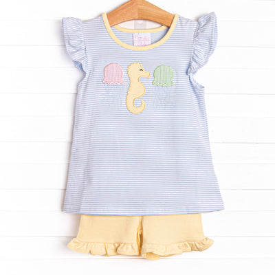 This set features a flutter sleeves top in a blue striped print, a seahorse applique, and yellow ruffle shorts to match.