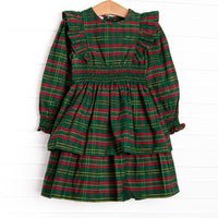  This dress features a green plaid print, ruffle trim, and elastic smocking. 