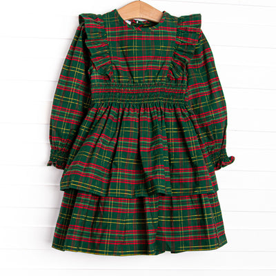  This dress features a green plaid print, ruffle trim, and elastic smocking. 